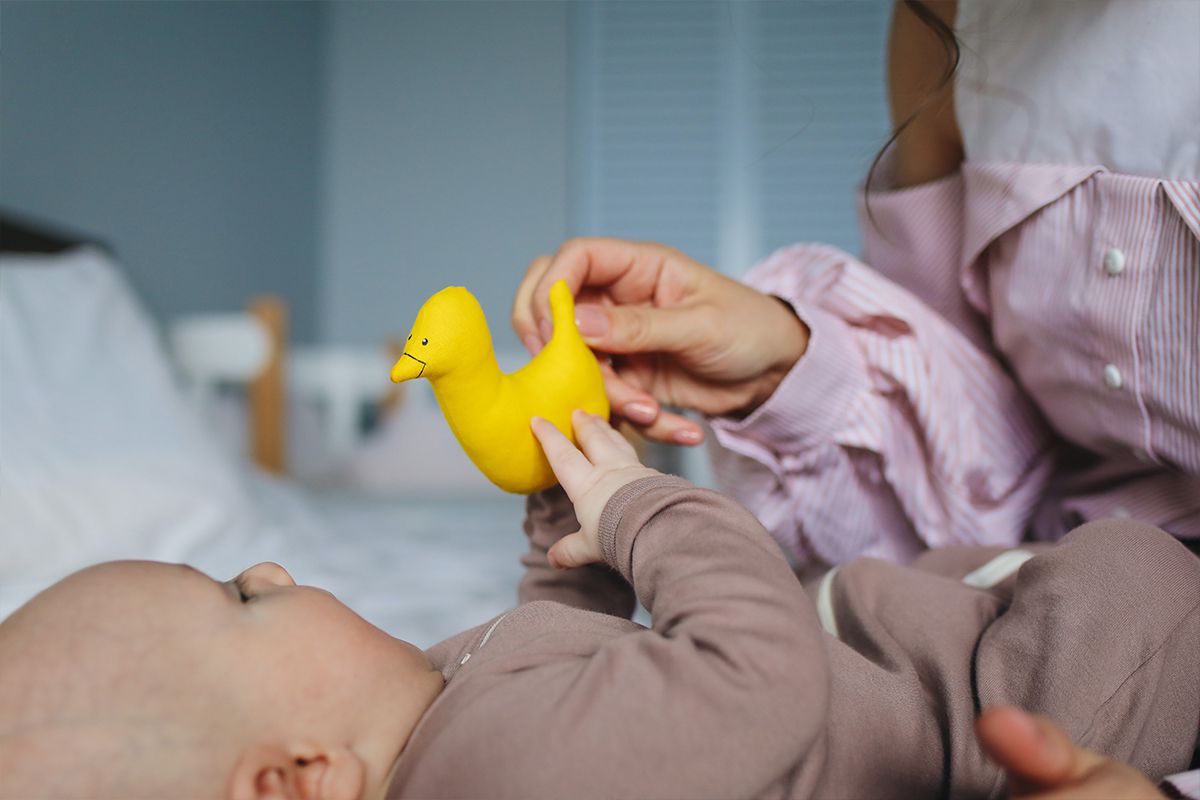 Bebé de menos de 6 meses fijando la atención en un pequeño peluche de juguete
